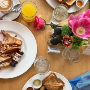 Table with various breakfast food plates and flowers