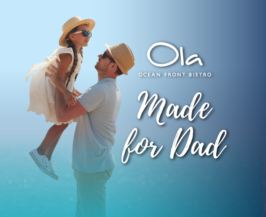 image of son seating on dad's shoulders looking at the ocean