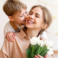 Son kissing Mother on the cheek with tulips in hand