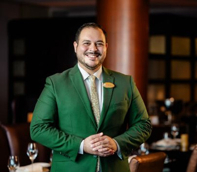 Bryan Solino in a green suit with a light green tie and a gold nametag