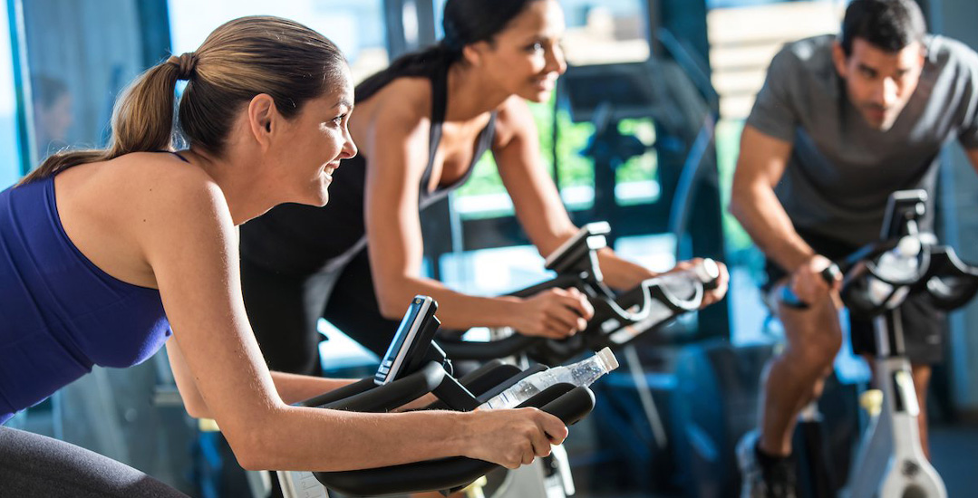 Three individuals engage in a cycling workout | Condado Vanderbilt Hotel